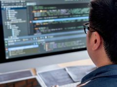 Programátor pracující na počítači s kódem, součást IT služeb společnosti Integra.